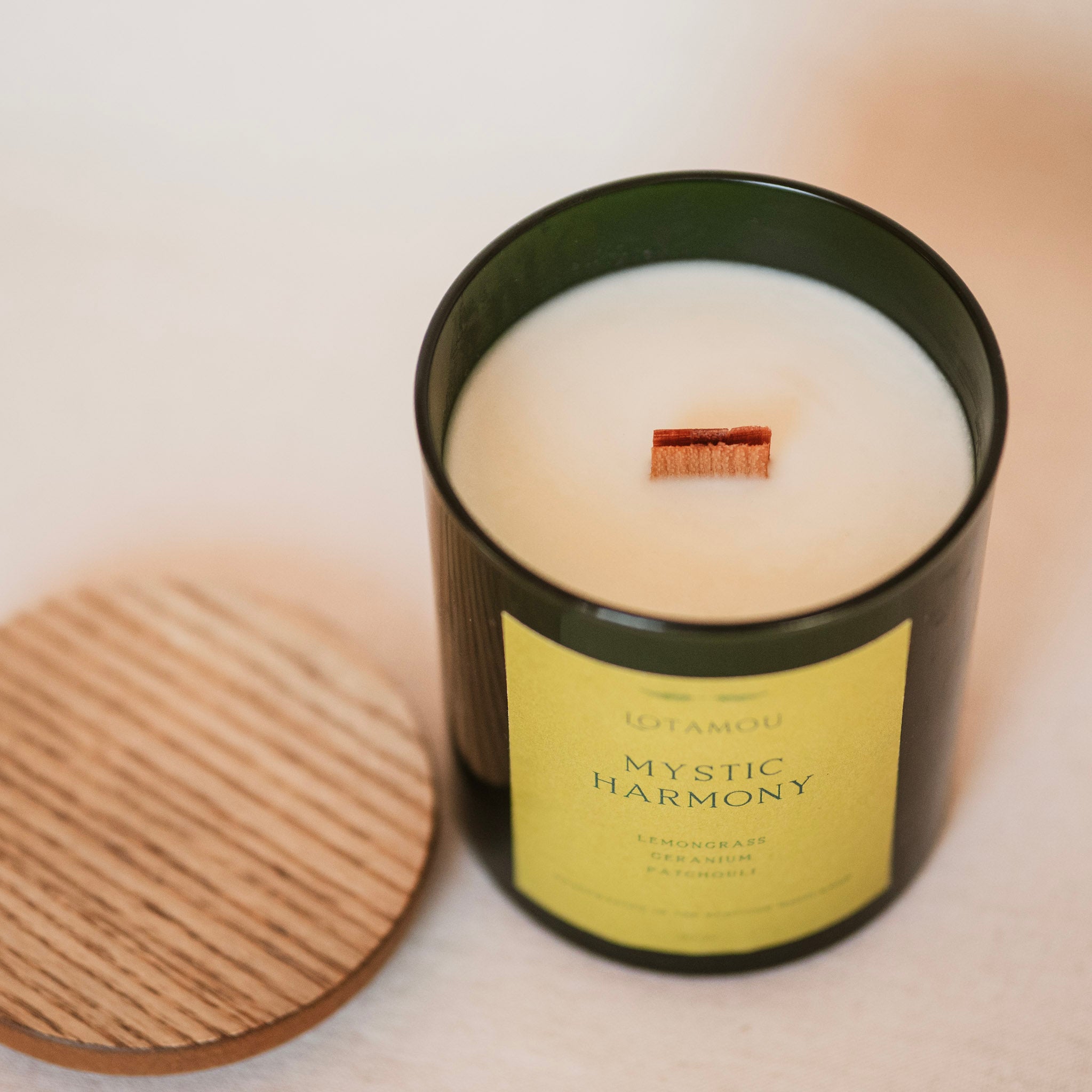 Candle in a black container with a wooden lid on a light surface