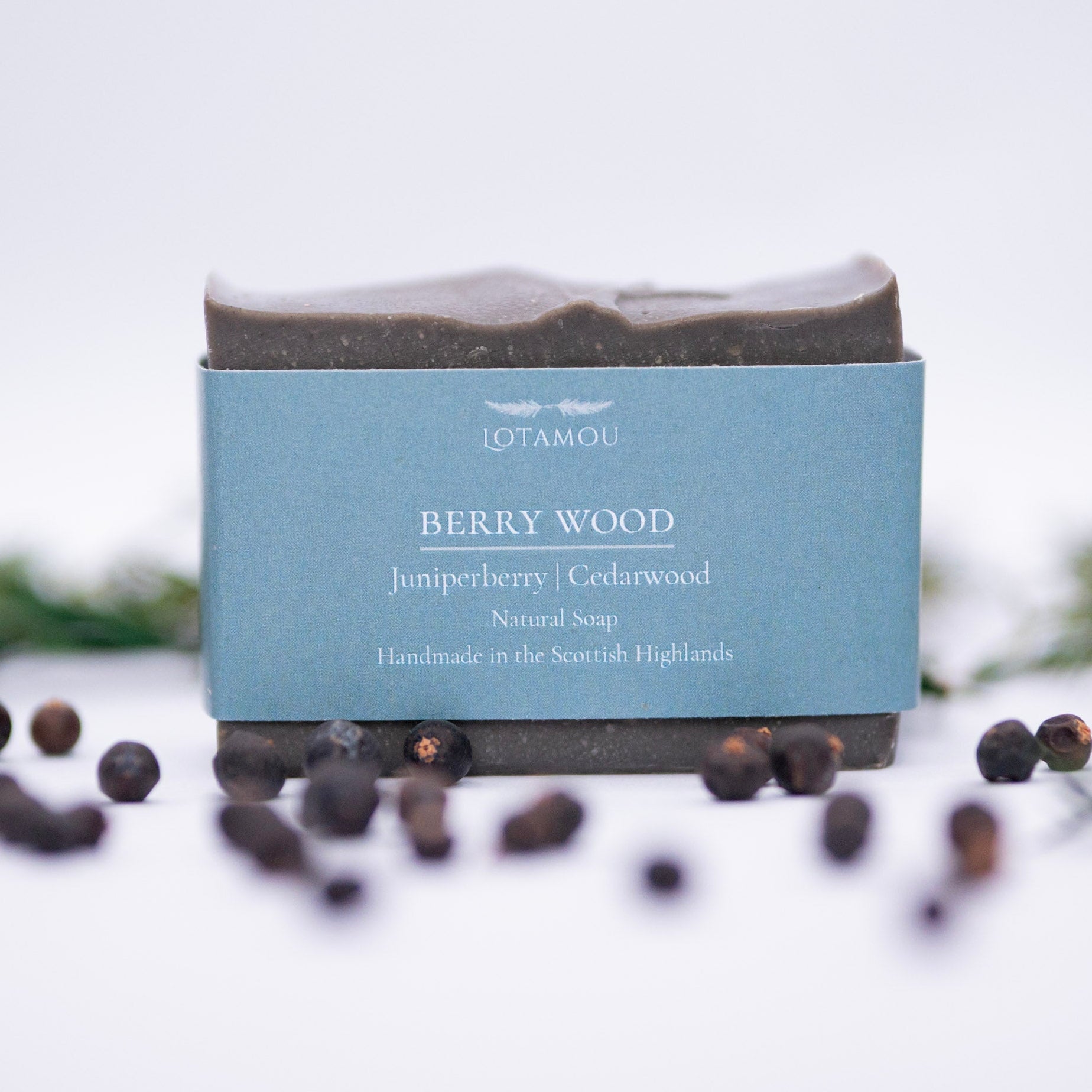 Bar of soap with a blue box labeled 'Berry Wood' on a white background with berries.