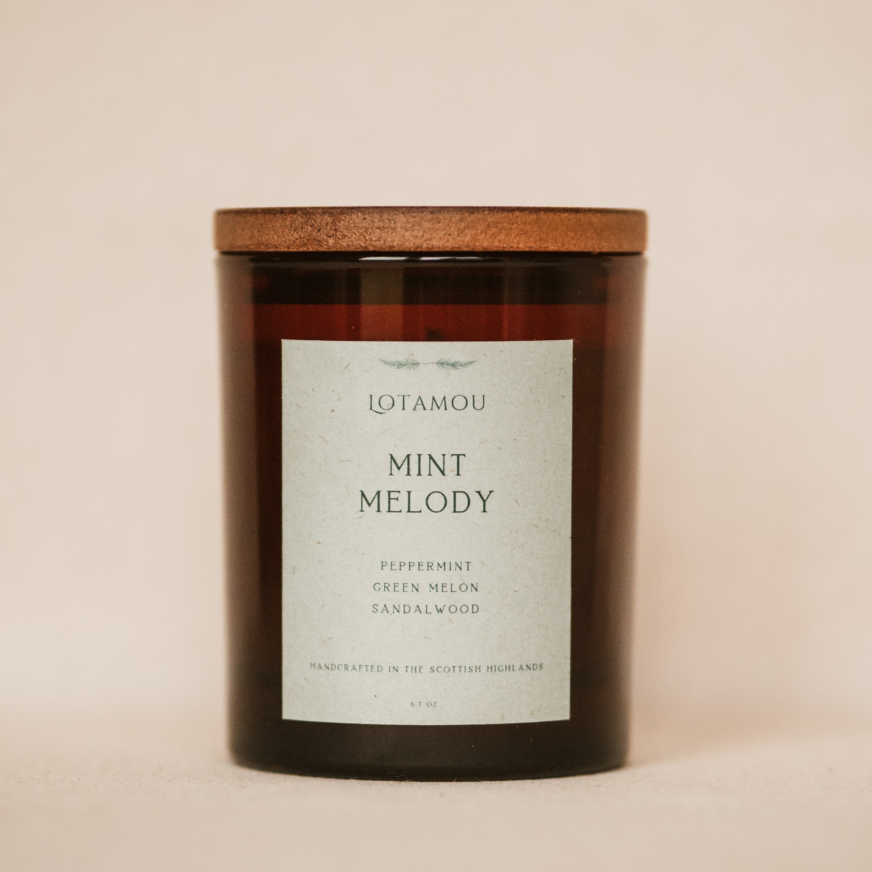 Candle with a wooden lid and 'LOTAMOU Mint Melody' label on a beige background