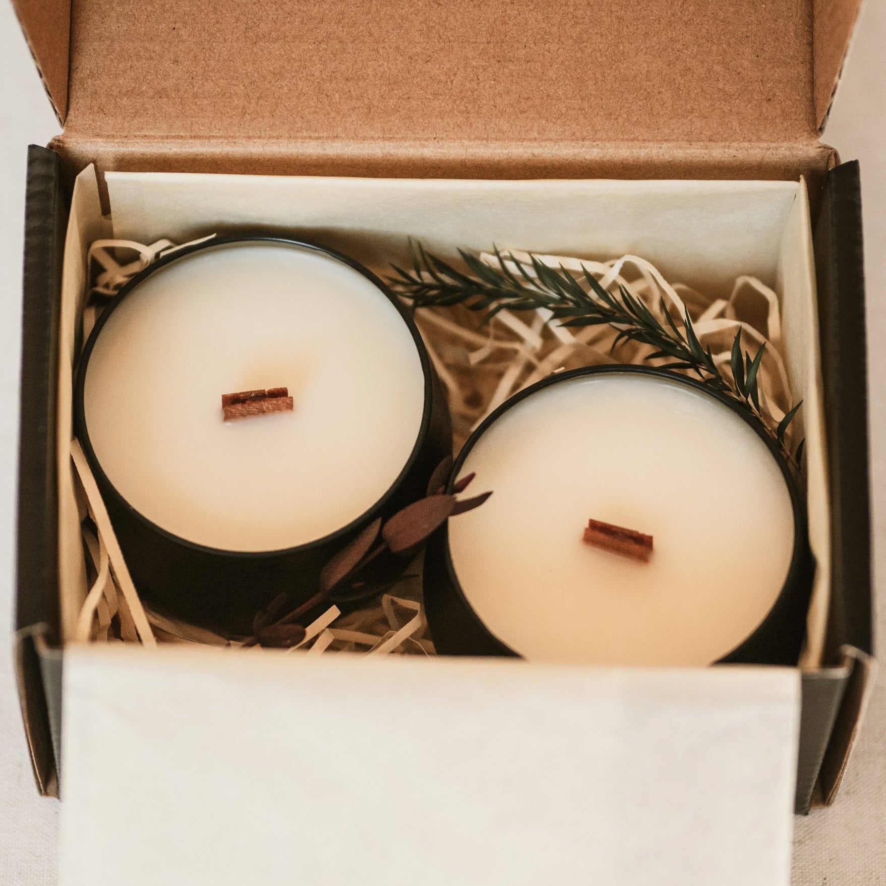 Two candles in a box with decorative elements on a neutral background