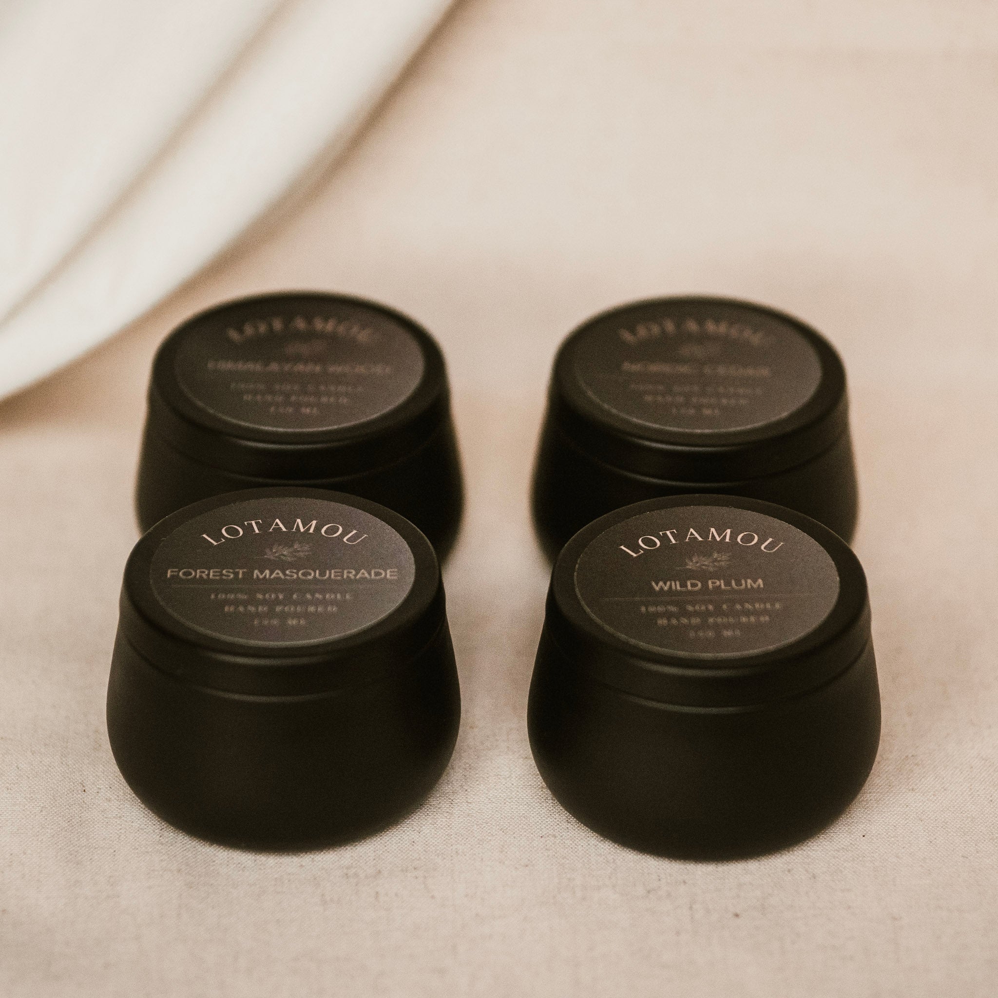Four black candles with labels on a beige surface