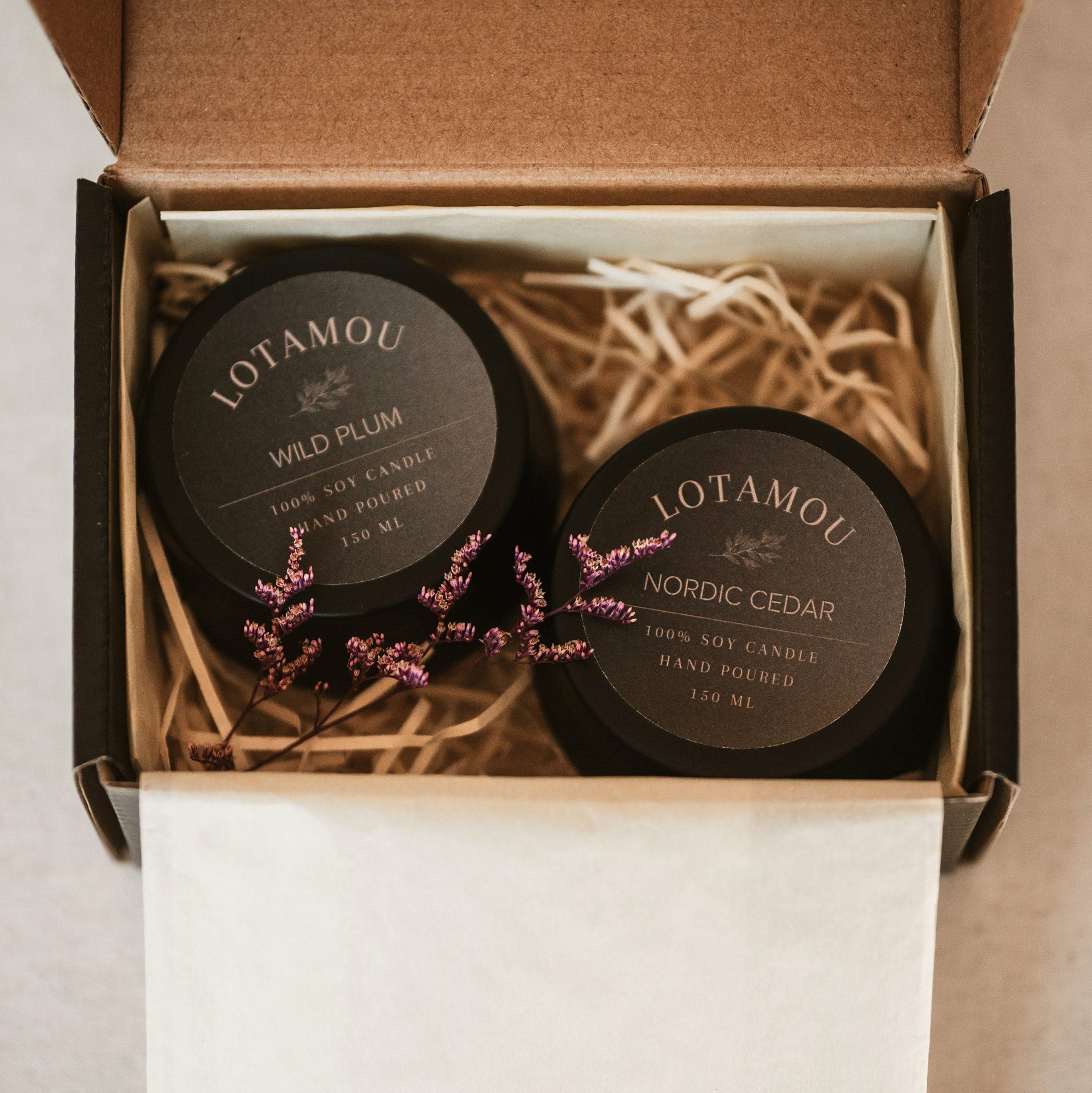 Two Lotamou candles in a box with decorative elements
