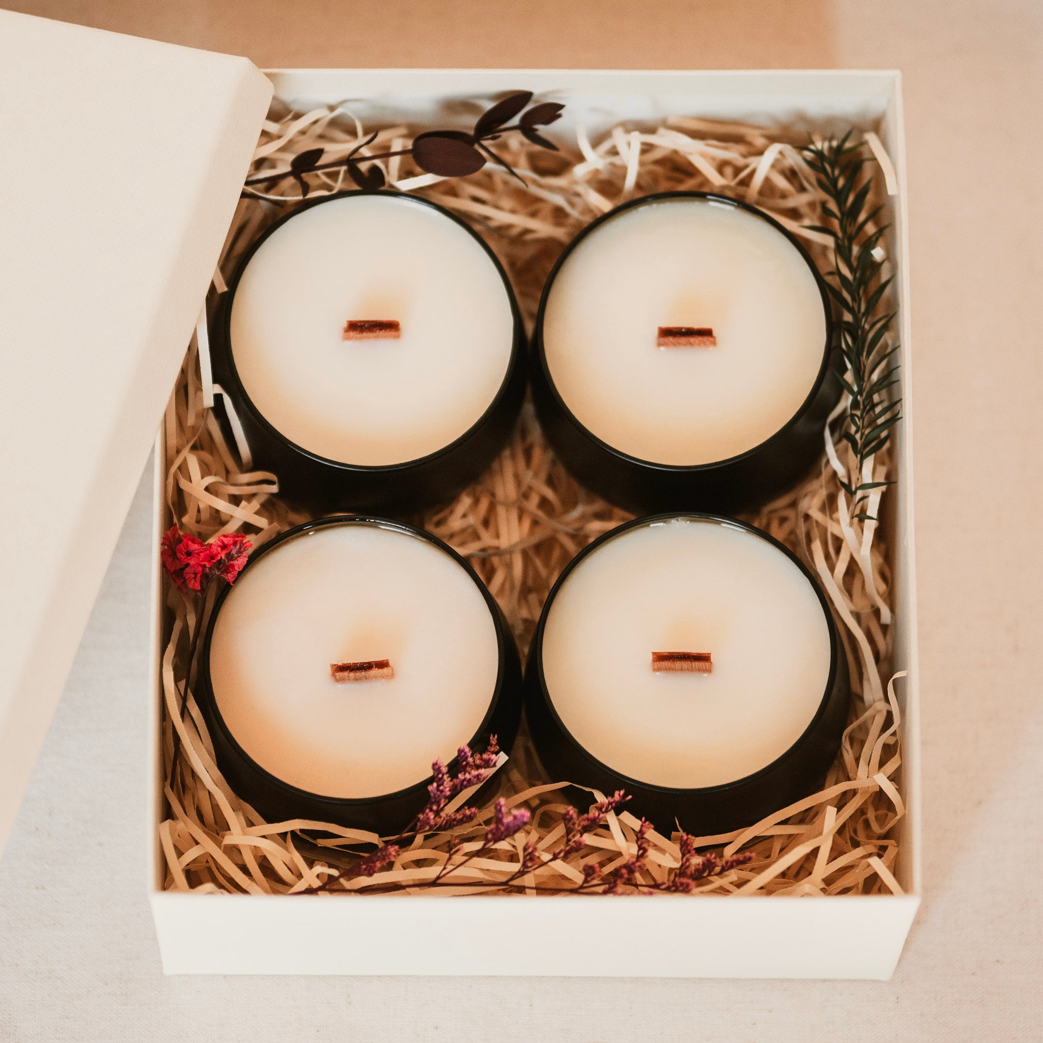 Four candles in a box with decorative straw and flowers