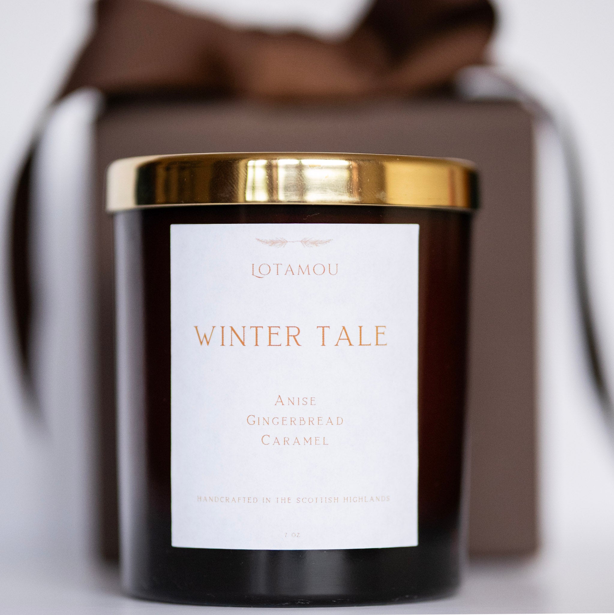 Candle with 'Winter Tale' label and gold lid on a white background
