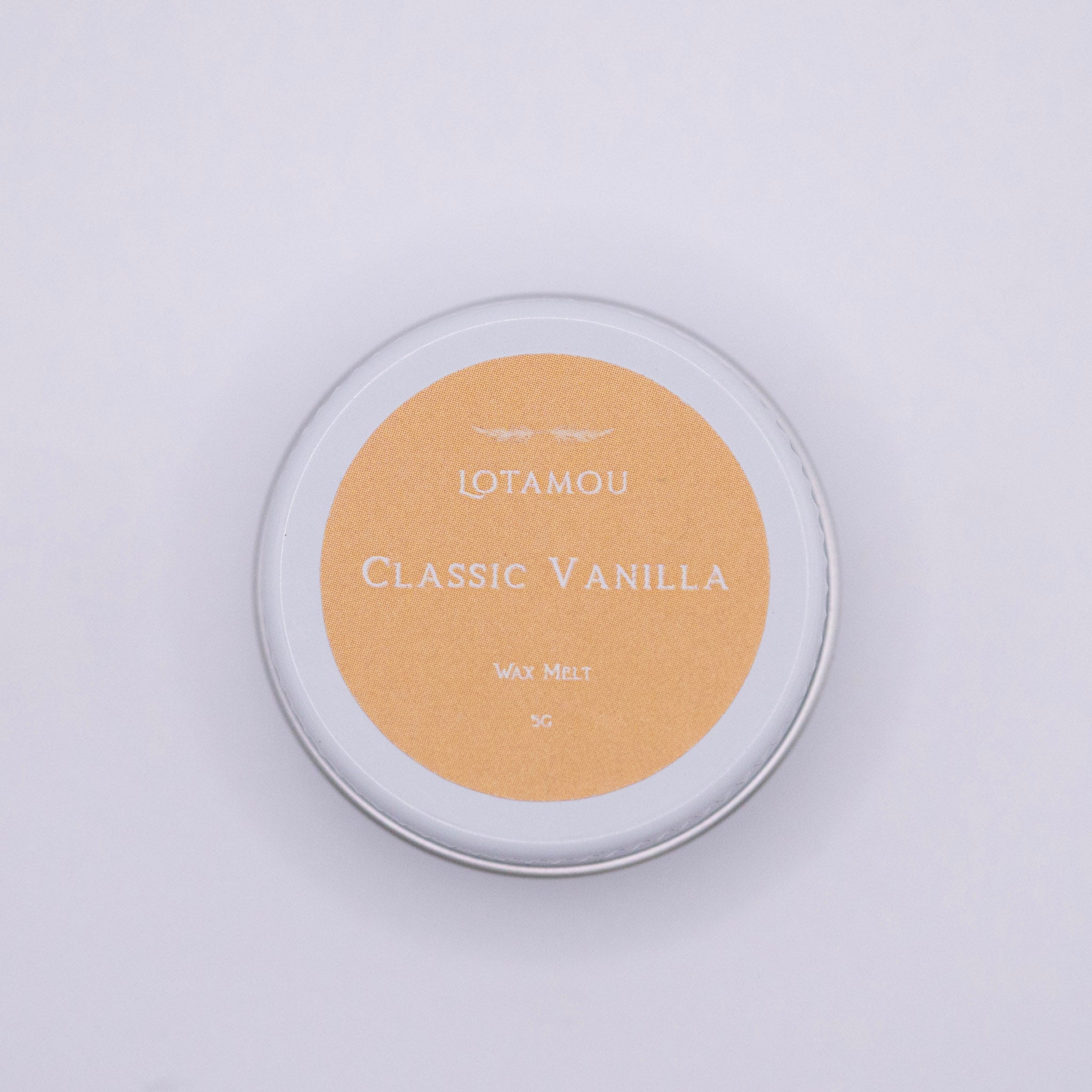 Tin of Lotamou Classic Vanilla wax melt on a light gray background