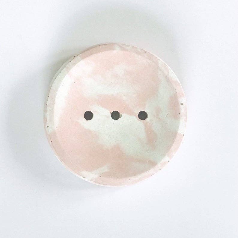 Round ceramic plate with a pink and white marbled design on a white background