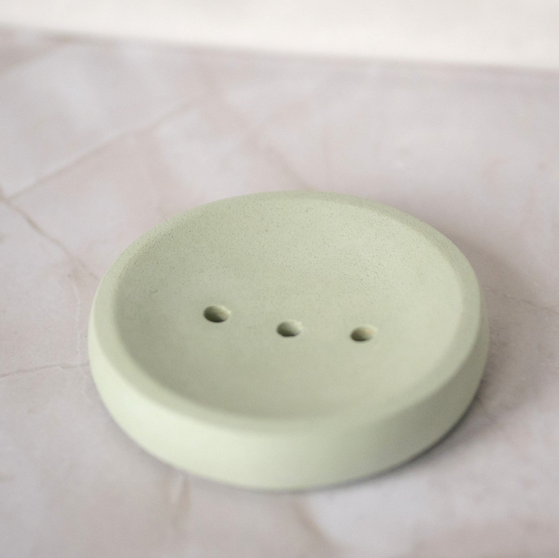 Light green ceramic soap dish on a white tiled surface