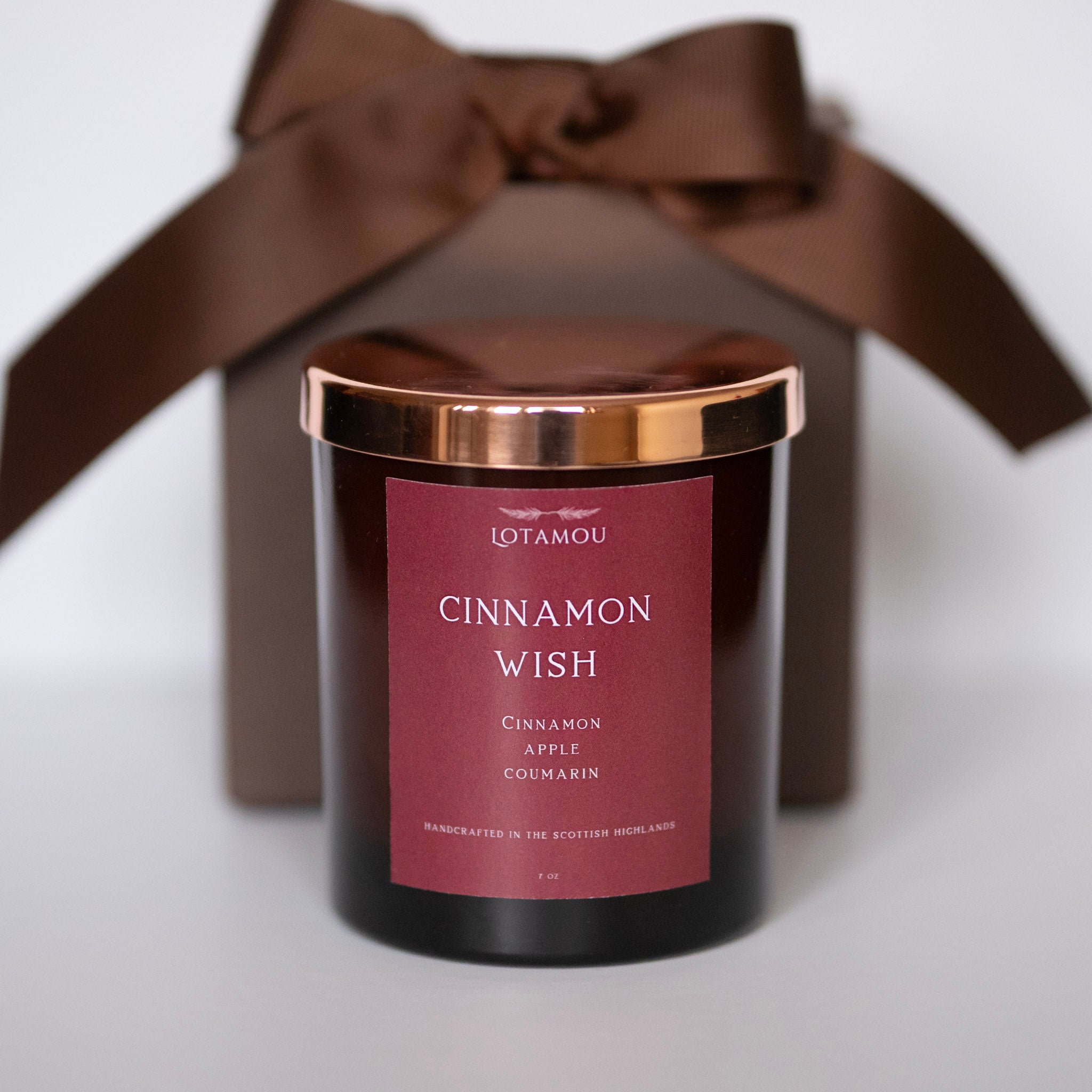 Candle with 'Cinnamon Wish' label and brown ribbon on a light background