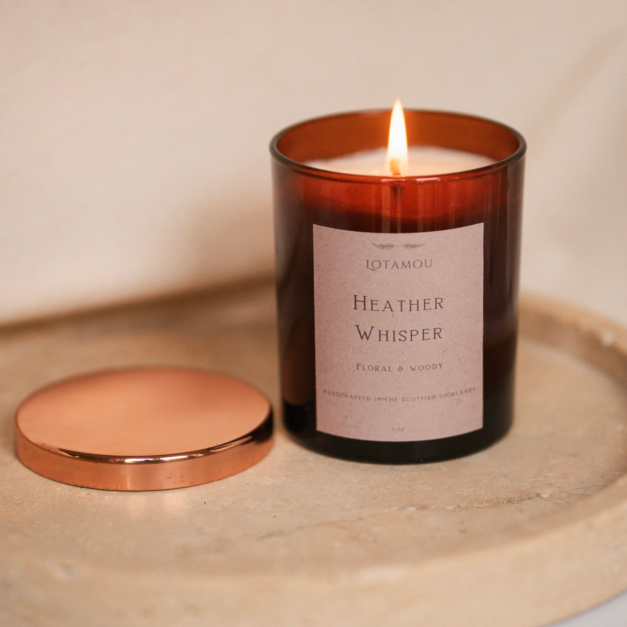 Candle labeled 'Heather Whisper' by Lotamou on a neutral background