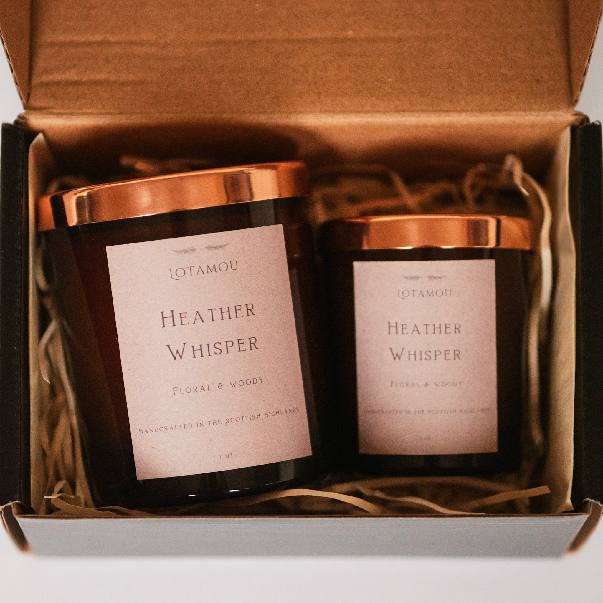 Two candles labeled 'Heather Whisper' in a gift box with brown interior.