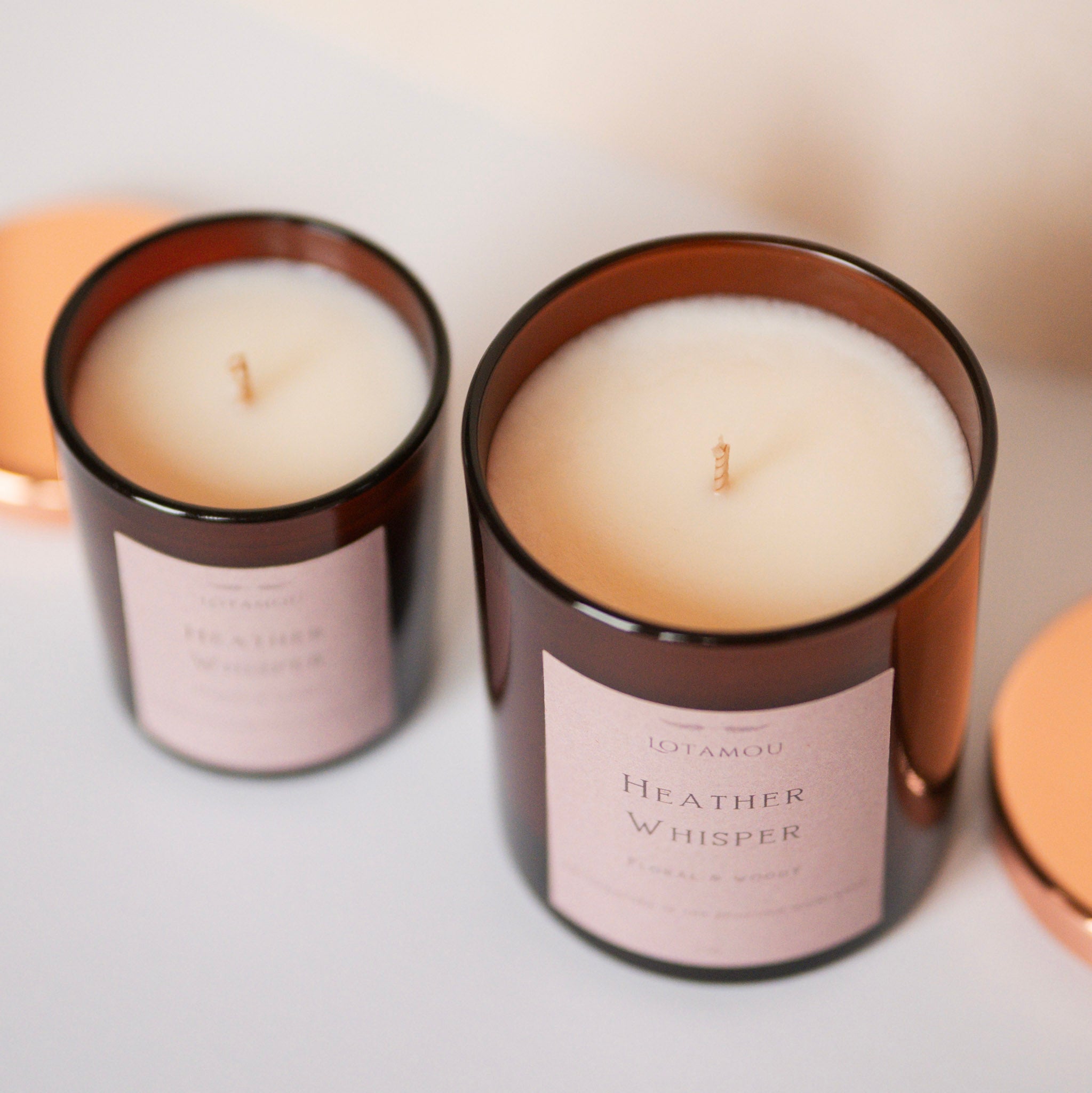 Two candles with 'Heather Whisper' label on a light background