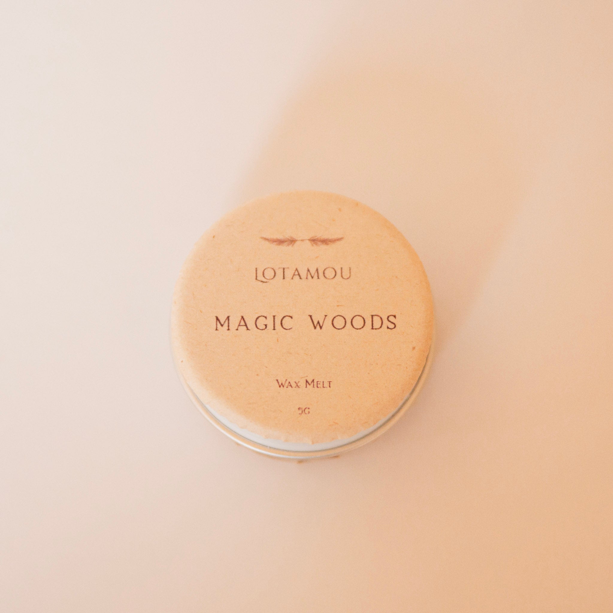 Round wax melt container labeled 'Magic Woods' by Lotamou on a beige background