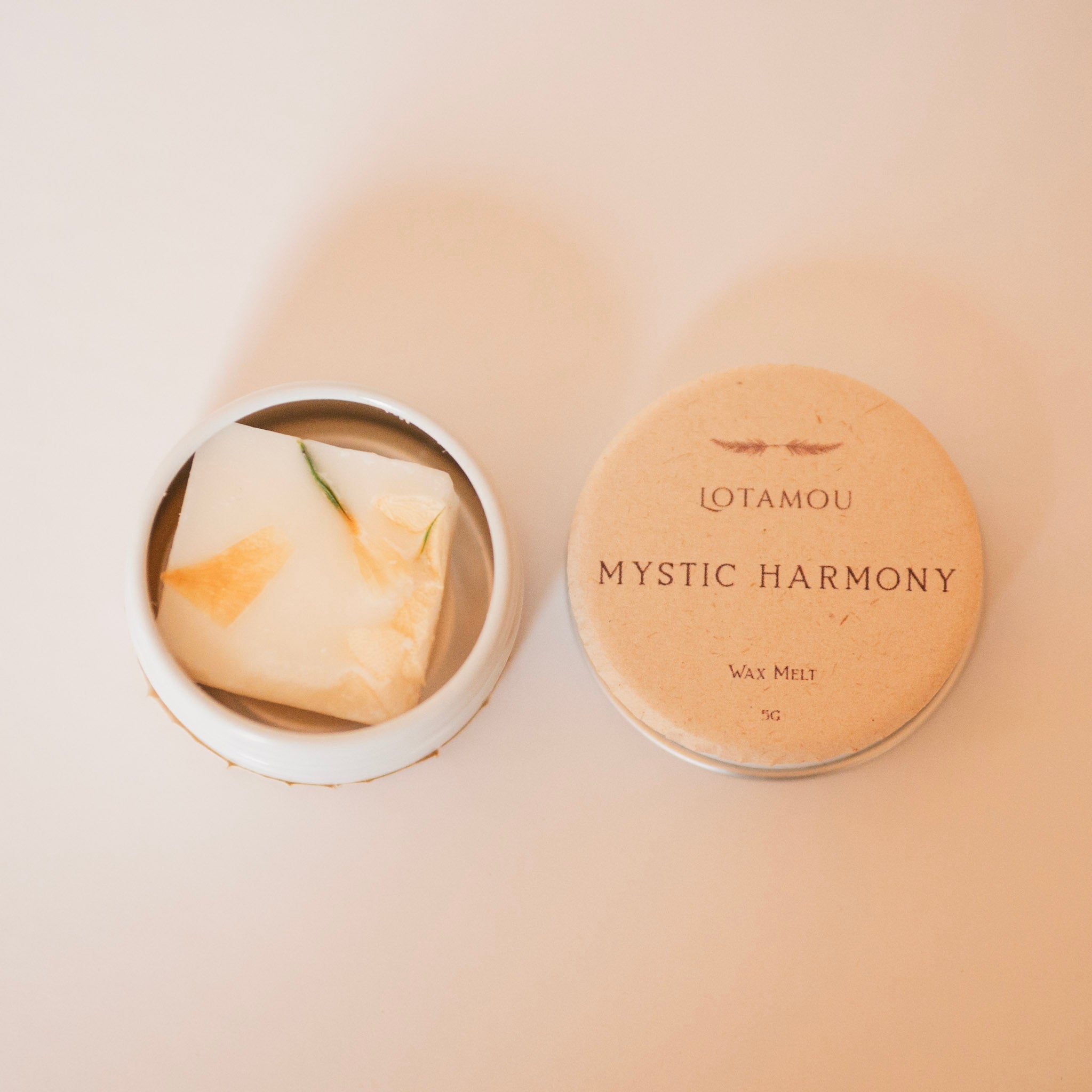 Wax melt in a container with 'OTAMOU Mystic Harmony' packaging on a beige background