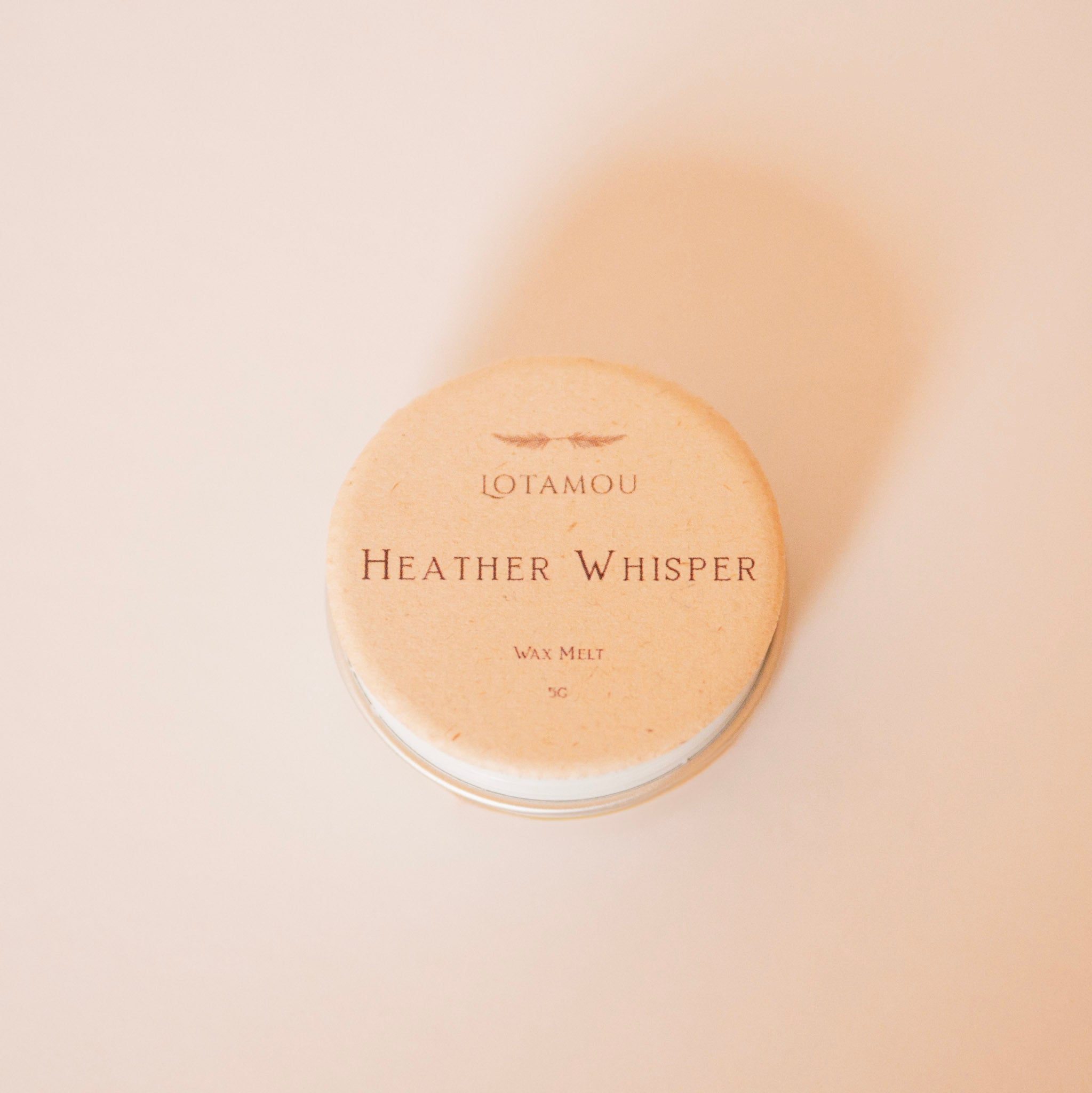 Wax melt container labeled 'Heather Whisper' by Lotamou on a beige background