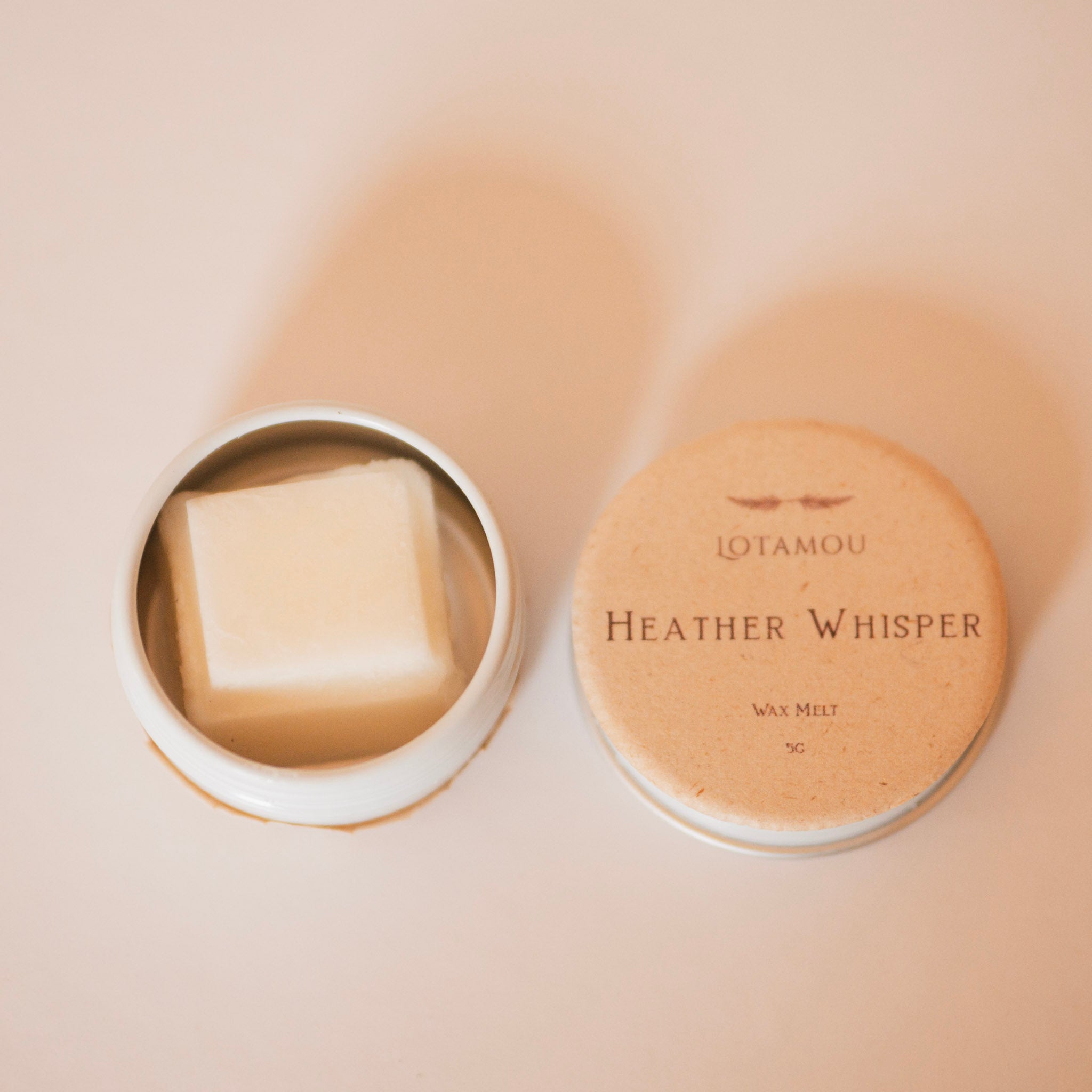 Wax melt in a container with 'LOTAMOU Heather Whisper' packaging on a beige background